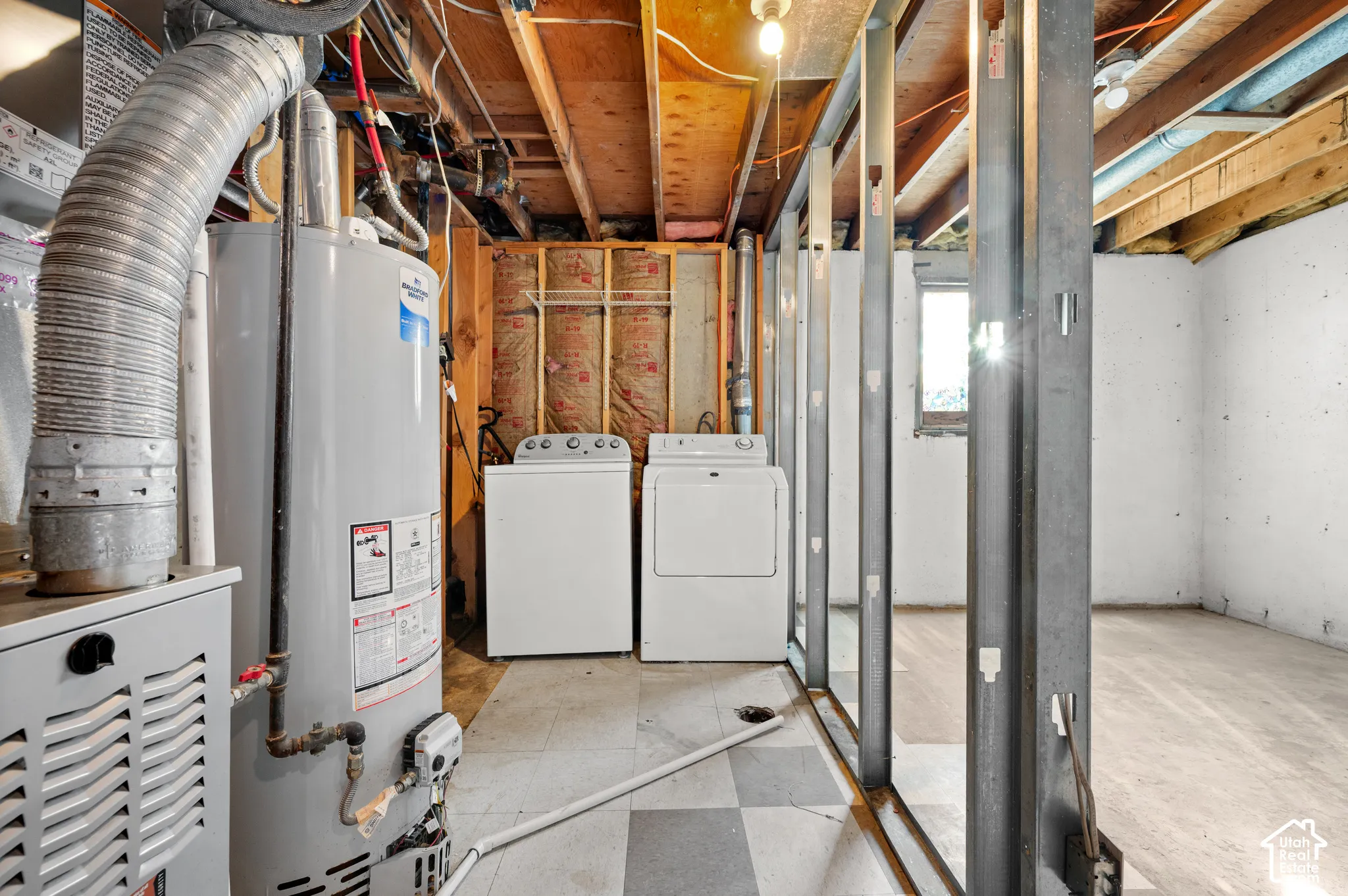 Unfinished utility area featuring exposed joist ceiling, metal wall stud framing, concrete walls, and vinyl tile flooring