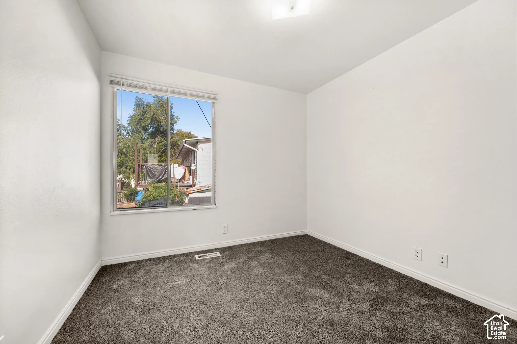 Neutral-toned walls, high-pile charcoal carpeting, and a sliding window featuring horizontal blinds