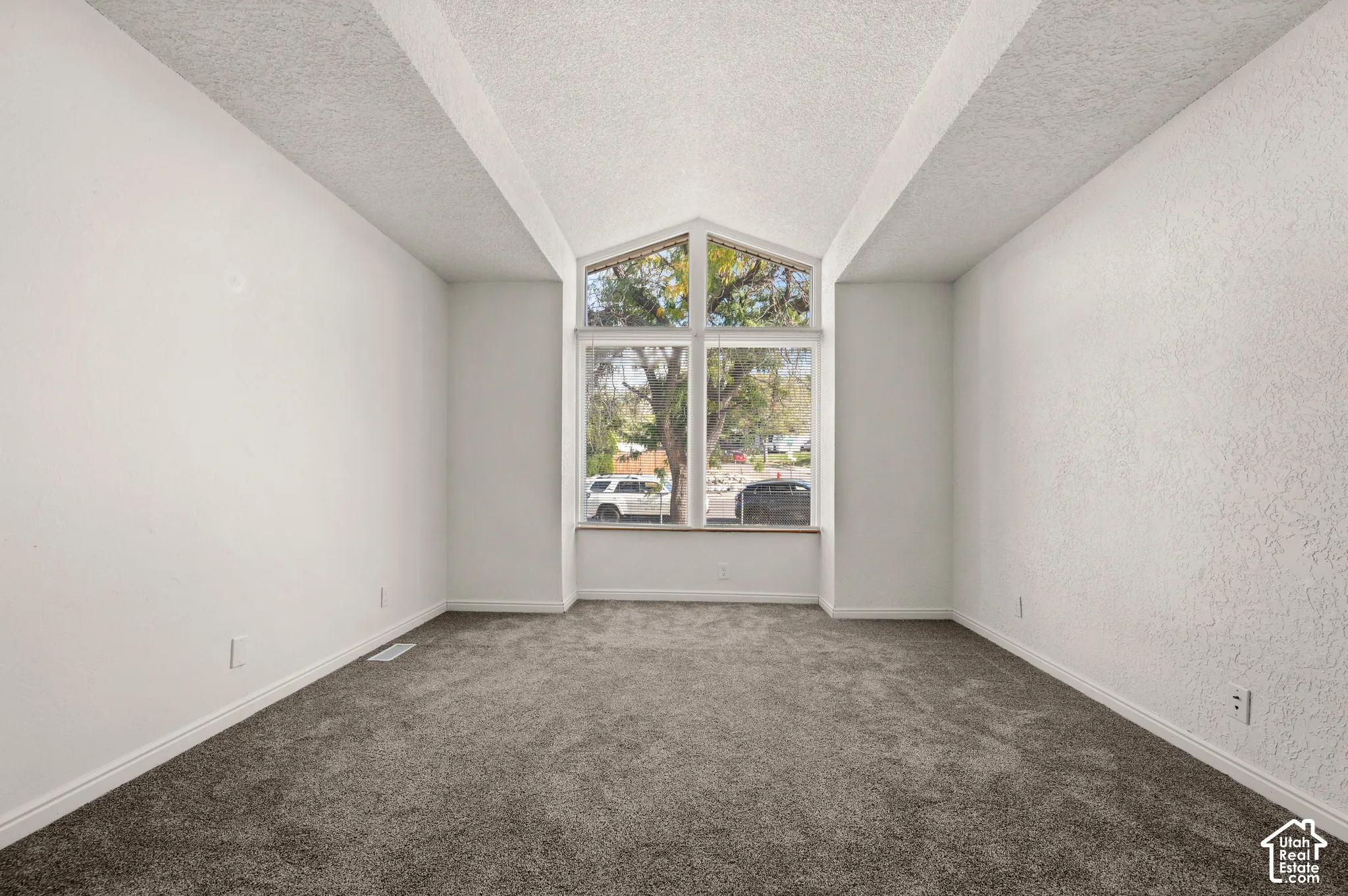 Vaulted ceiling with an architectural peak, wall-to-wall carpeting, and a prominent floor-to-ceiling window configuration