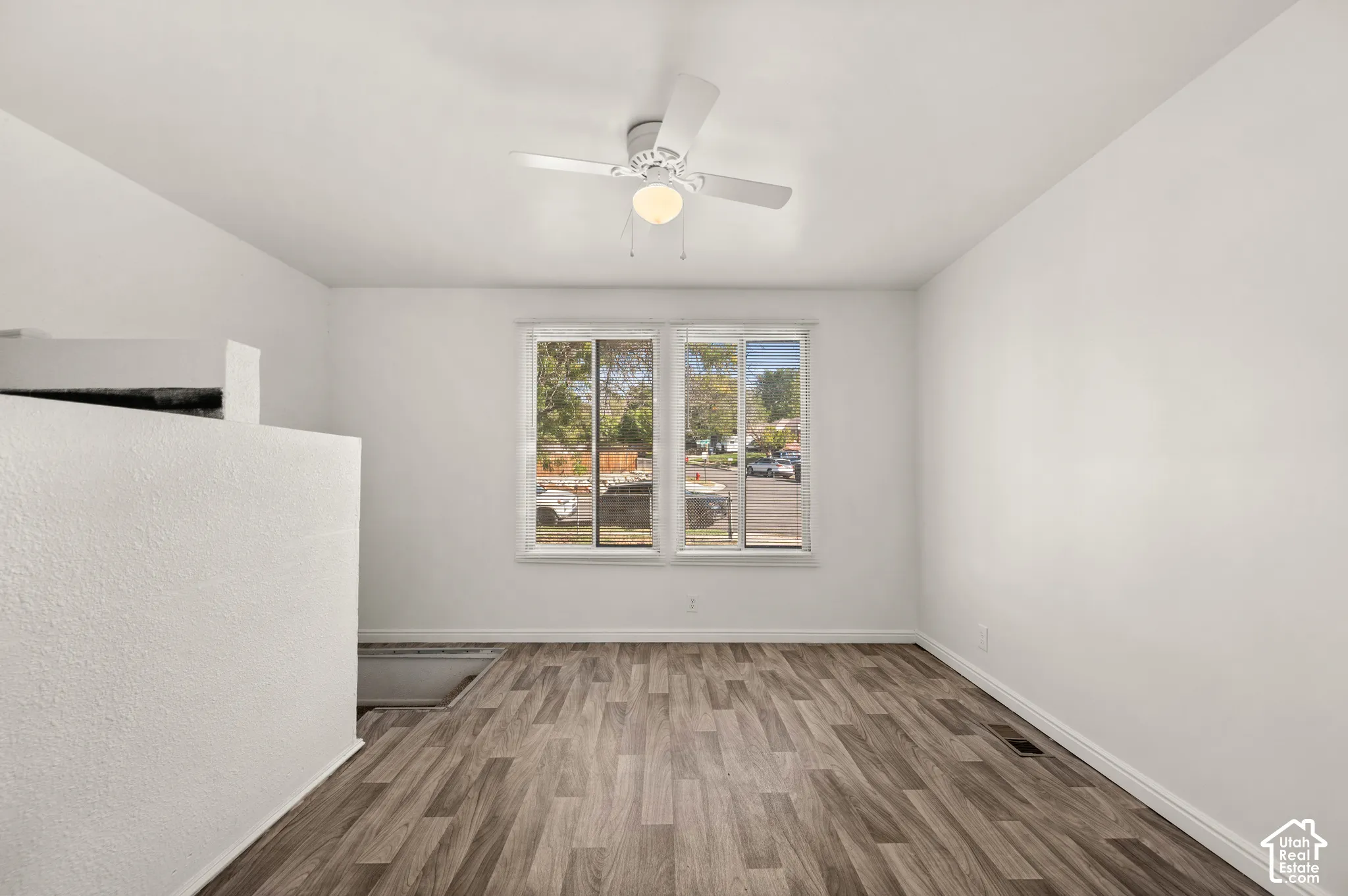 Neutral-toned interior featuring wood-finish flooring, dual-pane slider windows, and a ceiling-mounted light fixture with a central fan