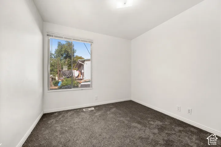 Neutral-toned walls, high-pile charcoal carpeting, and a sliding window featuring horizontal blinds