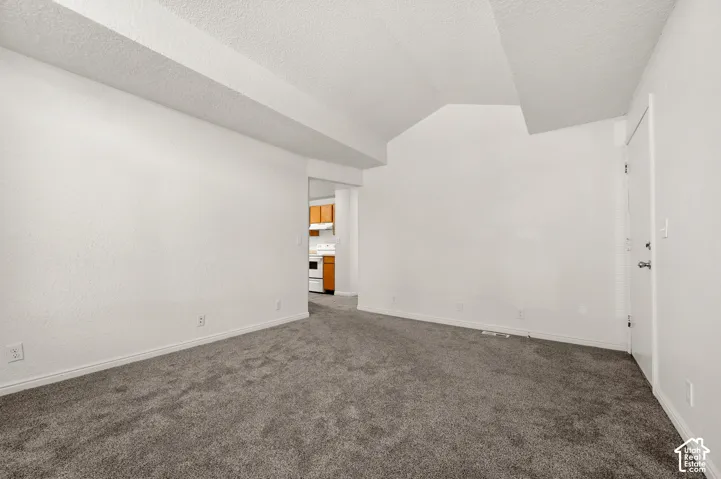 Room featuring vaulted ceilings, neutral wall tones, and wall-to-wall carpeting