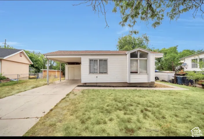 Exterior featuring white horizontal siding, an attached carport, a concrete driveway, and a prominent multi-paneled bay window
