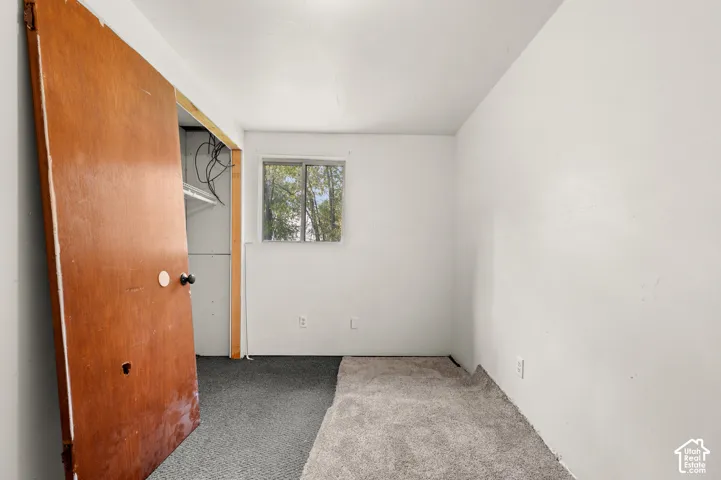Room featuring carpeted flooring, a sliding window, and a wood-finish interior door