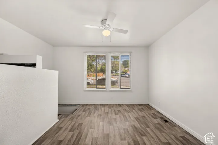 Neutral-toned interior featuring wood-finish flooring, dual-pane slider windows, and a ceiling-mounted light fixture with a central fan