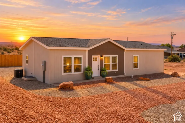Single-story exterior featuring two-tone vertical siding, a gable roofline, multi-pane entry door, and desert-style gravel landscaping