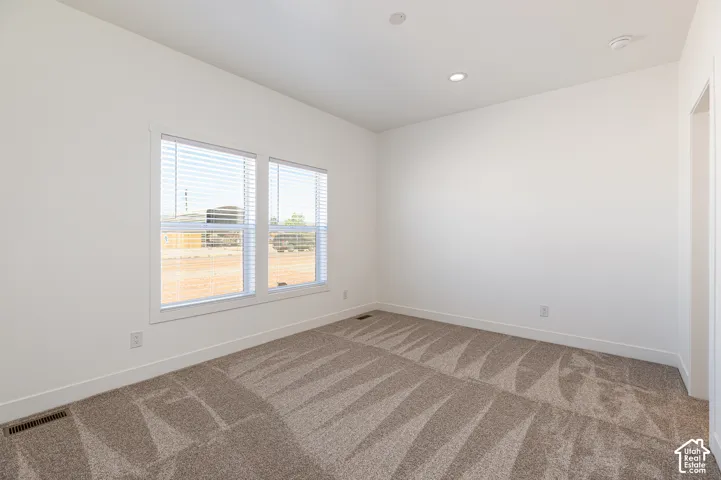 Neutral-toned wall-to-wall carpeting, crisp white walls, recessed ceiling lighting, and double-pane windows with horizontal blinds