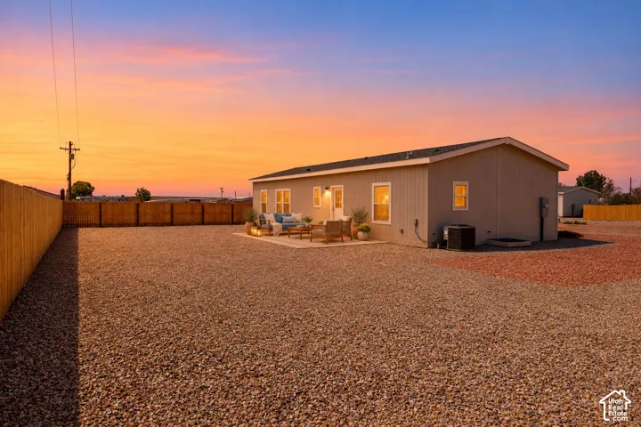 Expansive exterior space featuring a fenced perimeter, stone-ground landscaping, and a concrete patio