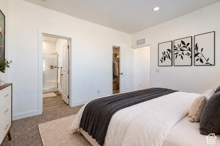 Bedroom featuring neutral carpeting, recessed lighting, a walk-in closet, and an en-suite bathroom with a glass-enclosed shower and wood-finish flooring