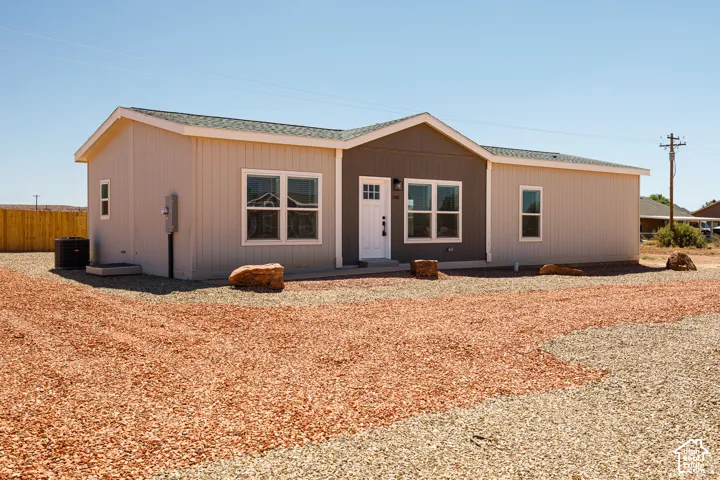 Single-story residence featuring vertical panel siding, a dual-tone exterior color palette, an asphalt shingle roof, and a low-maintenance gravel landscape