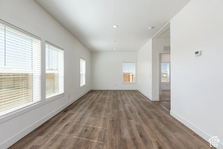 Interior space featuring wood-finish flooring, recessed lighting, and multiple windows with horizontal blinds