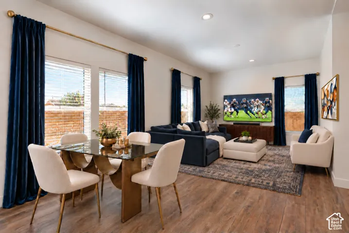 Open-concept interior featuring wood-finish flooring, recessed lighting, and multiple large windows with metal curtain rods