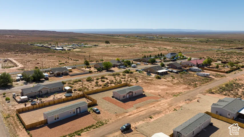 Aerial perspective of the residential lot featuring a gravel-surfaced yard, wood-style privacy fencing, and native desert terrain
