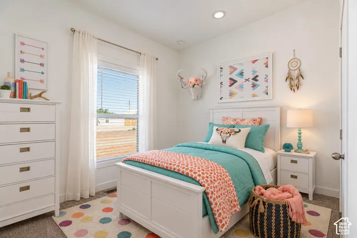 Neutral wall finishes, recessed ceiling lighting, and carpeted flooring, featuring a large window with horizontal blinds