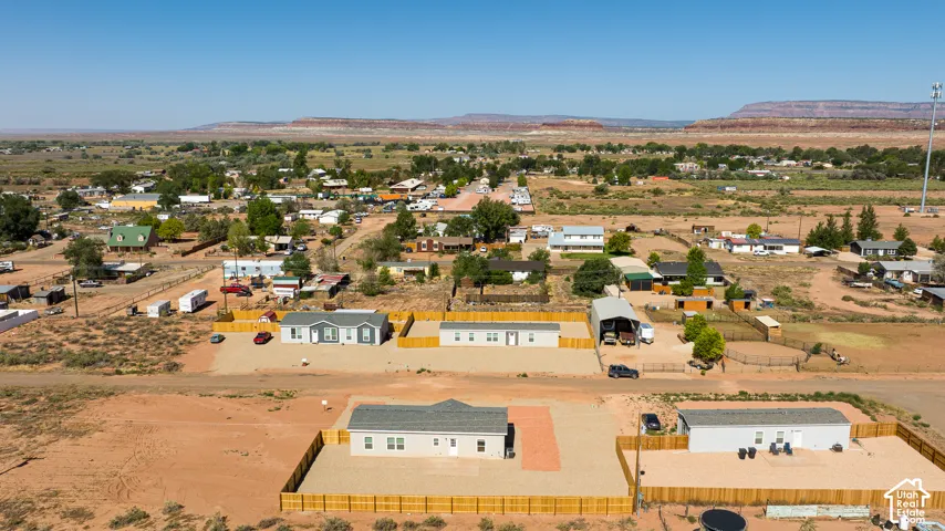 Aerial perspective of properties featuring perimeter wood fencing, gravel-surfaced lots, and desert mountain topography