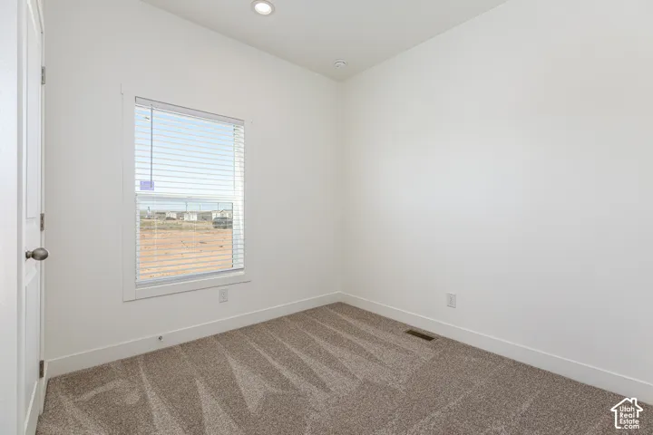 Neutral-toned carpeted flooring, single-pane window with horizontal blinds, and recessed lighting