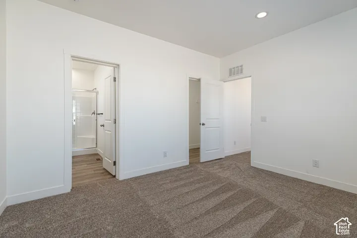 Neutral-toned carpeting, recessed ceiling lighting, and solid-core paneled doors