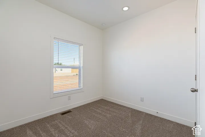Neutral wall paint, plush carpeting, recessed lighting, and a single-pane window with horizontal blinds