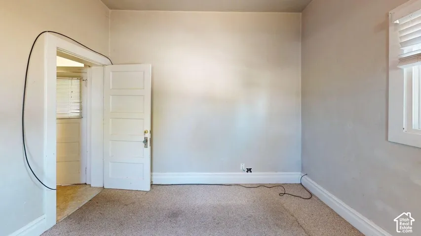 Interior space featuring neutral-toned walls, a classic five-panel wood door, and a window with horizontal blinds