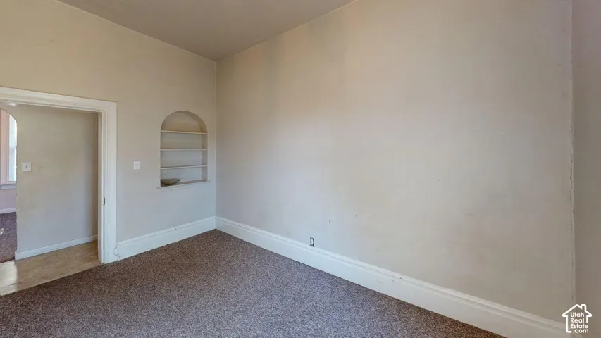 Room featuring carpeted flooring and a built-in arched wall niche with integrated shelving