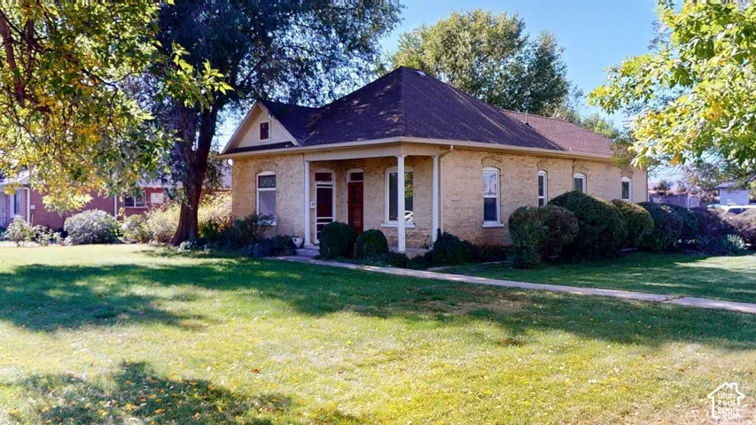 Single-story brick exterior featuring a covered front porch, a hip roof, arched window casings, and expansive grounds