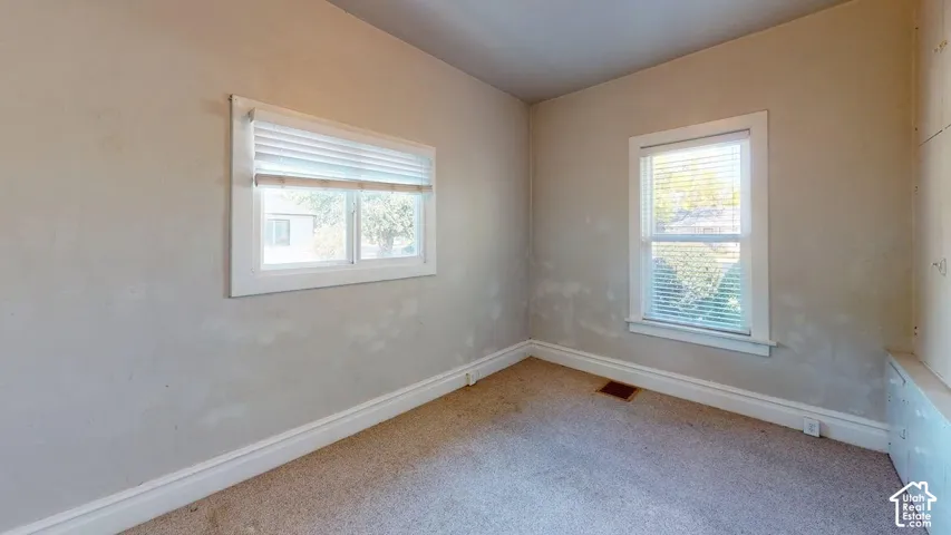 Interior room featuring two double-pane sliding windows with integrated blinds, wall-to-wall carpeting, and built-in floor-to-ceiling cabinetry