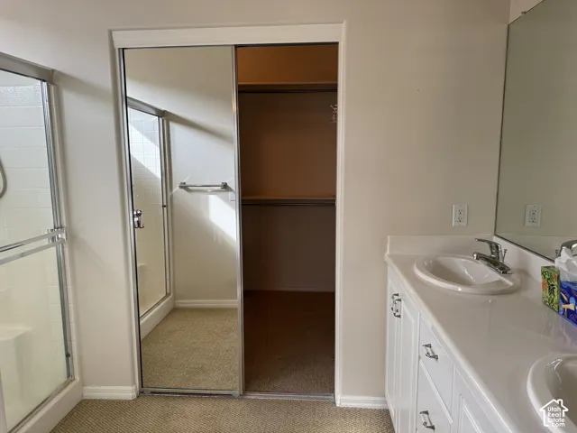 Vanity with solid-surface countertop and dual integrated sinks, sliding mirrored closet doors, built-in shelving, and enclosed shower stall