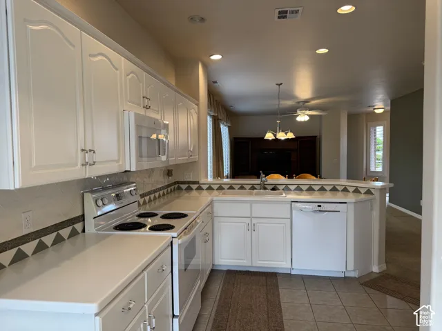 Kitchen featuring white cabinetry, solid surface countertops, patterned decorative tile backsplash, built-in electric range, and integrated dishwasher