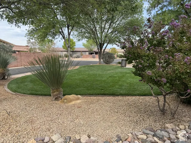 Landscaped grounds featuring a manicured lawn, stone curbing, mature trees, ornamental shrubbery, and gravel surfacing