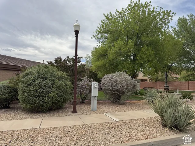 Landscaped grounds featuring mature trees, manicured shrubs, aggregate ground cover, and a decorative post lamp