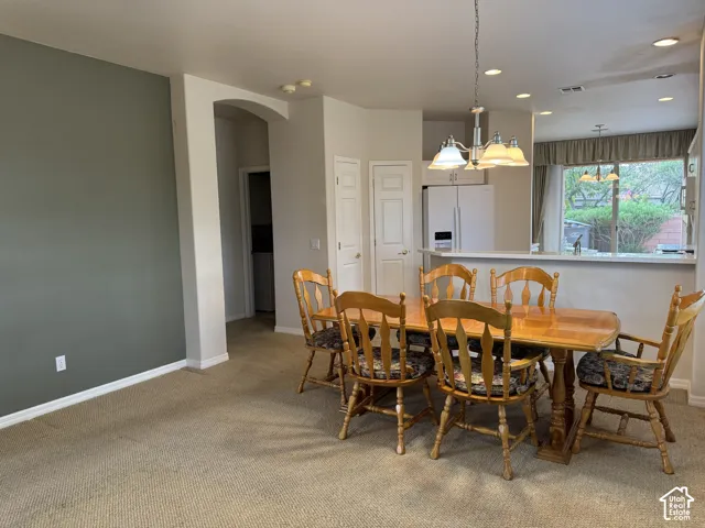 Open-concept dining area featuring a distinctive accent wall, arched architectural detailing, recessed lighting, and a multi-arm chandelier