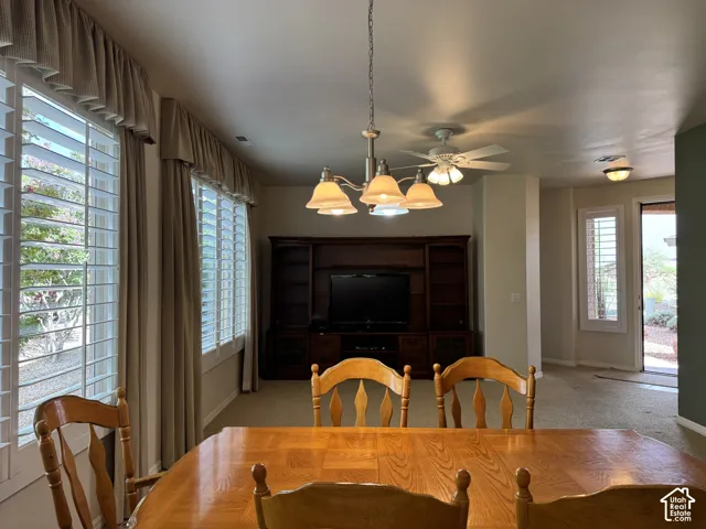 Built-in wooden entertainment center with integrated shelving, multi-arm chandelier with frosted glass shades, and custom plantation shutters