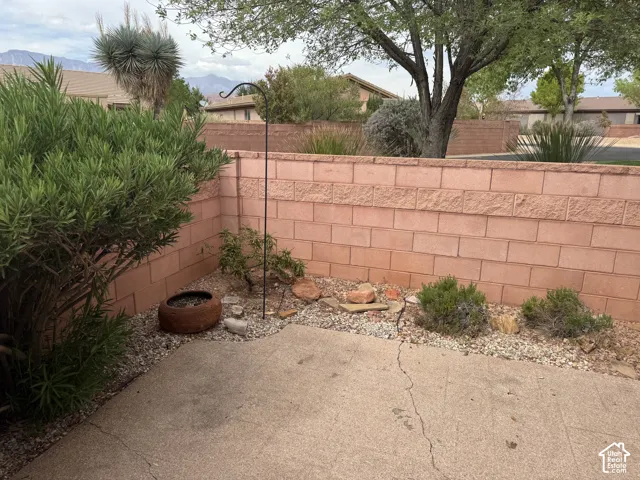 Concrete patio area enclosed by a masonry block wall, accented by xeriscaped ground cover, indigenous shrubbery, and mountain backdrop