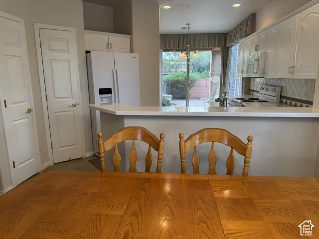 Kitchen featuring white cabinetry, solid-surface breakfast bar, tiled backsplash, built-in pantry, and recessed lighting