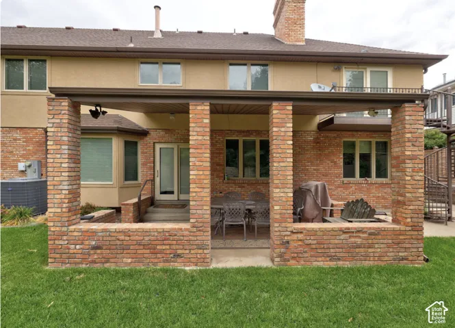 Covered masonry patio featuring brick support pillars, low-profile brick retaining walls, and a spiral staircase