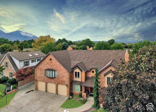 Brick exterior with a multi-gabled roofline, three-car garage, and mountain backdrop