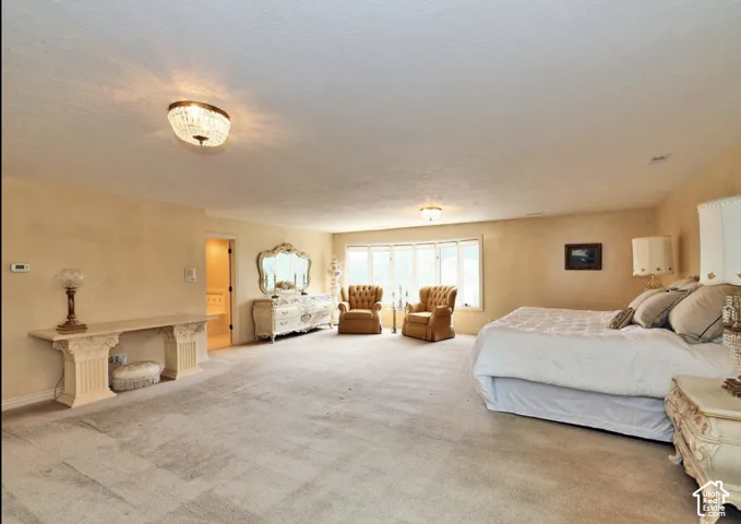 Expansive interior space featuring a large bay window, wall-to-wall carpeting, and two flush-mount crystal-style light fixtures