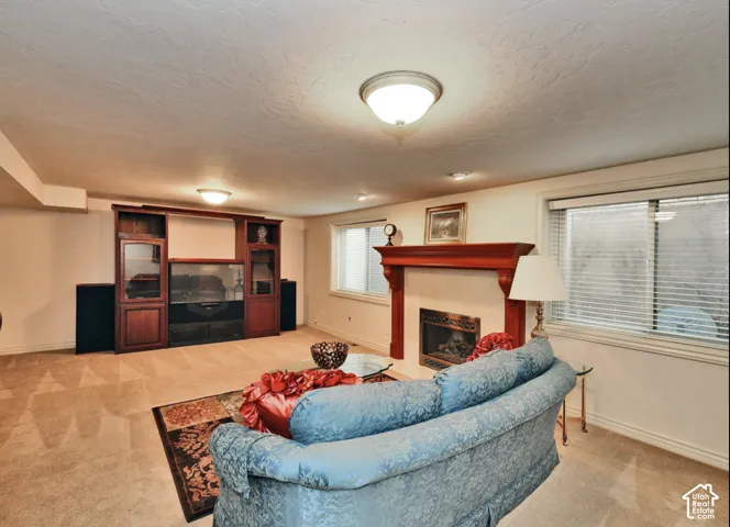 Spacious room featuring a fireplace with a wood-finish mantel, built-in wooden media cabinetry, flush-mount ceiling lighting, and horizontal window blinds