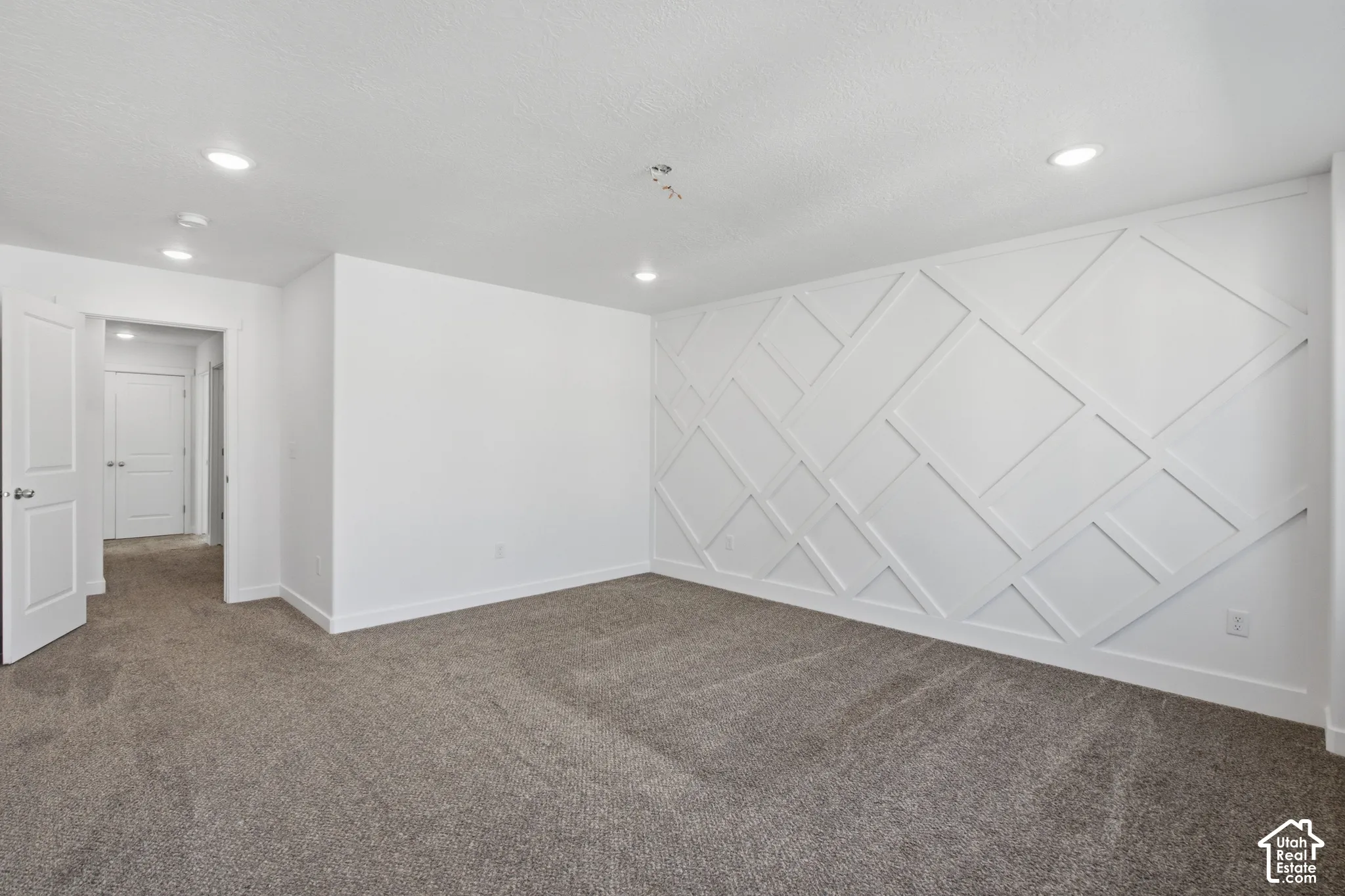 Interior space featuring wall-to-wall carpeting, recessed ceiling lighting, and a geometric wood wall treatment