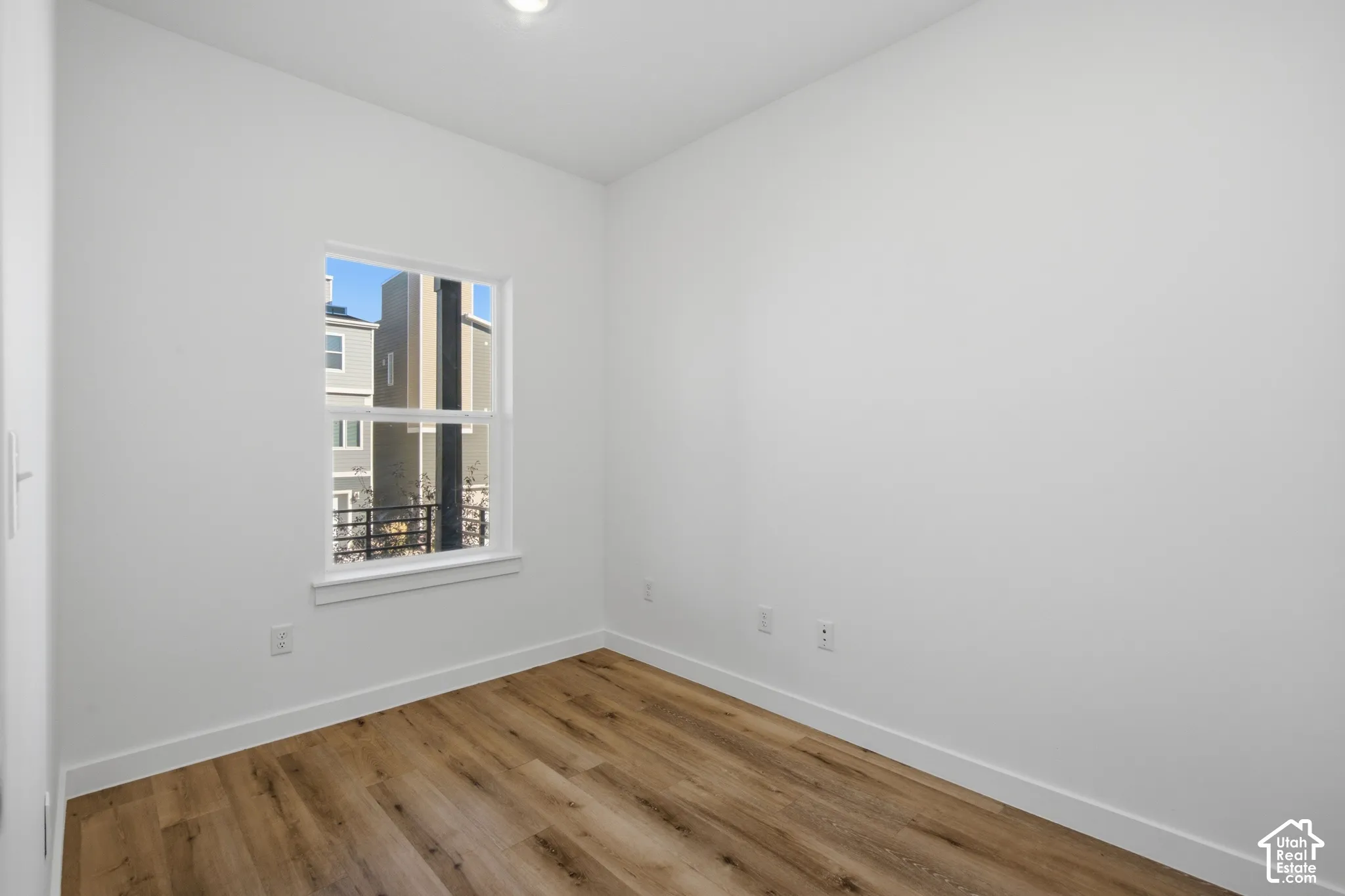Interior room featuring wood-finish flooring, white walls, and a recessed ceiling light