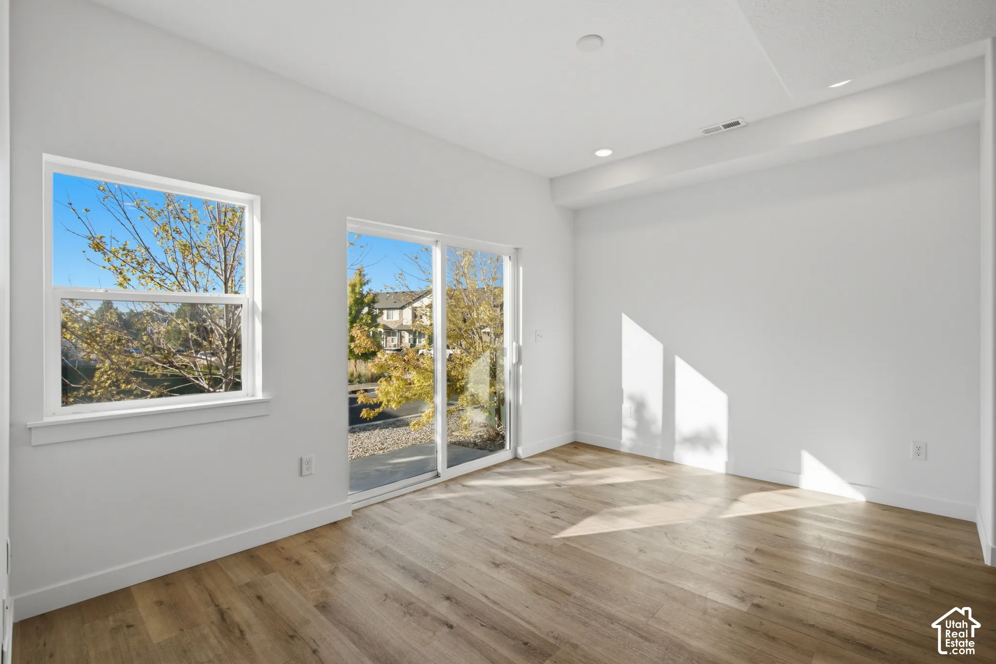Neutral-toned interior featuring wood-finish flooring, recessed lighting, expansive sliding glass doors, and a single-hung window
