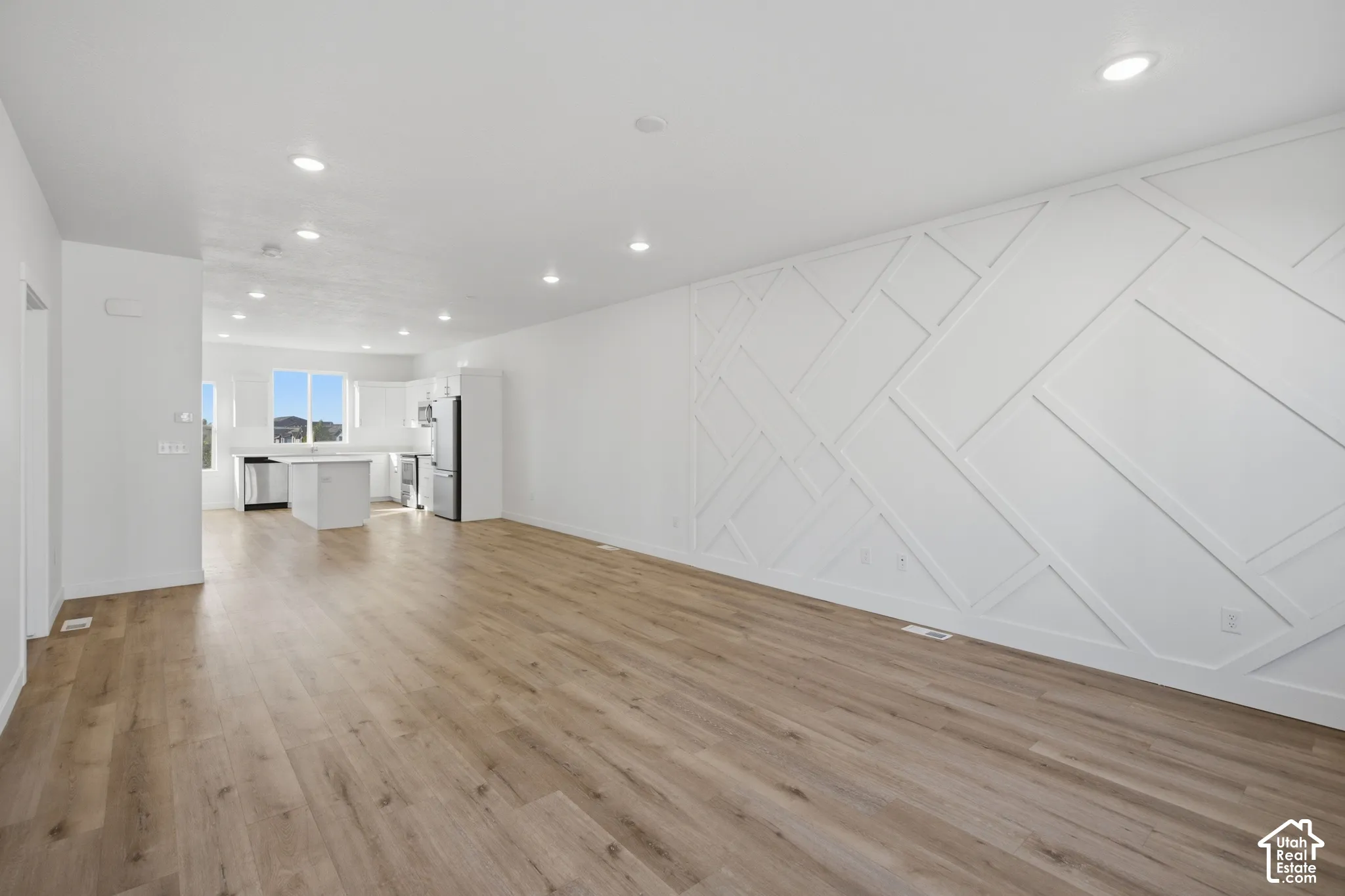 Open-concept area featuring wood-finish flooring, recessed lighting, and a geometric accent wall
