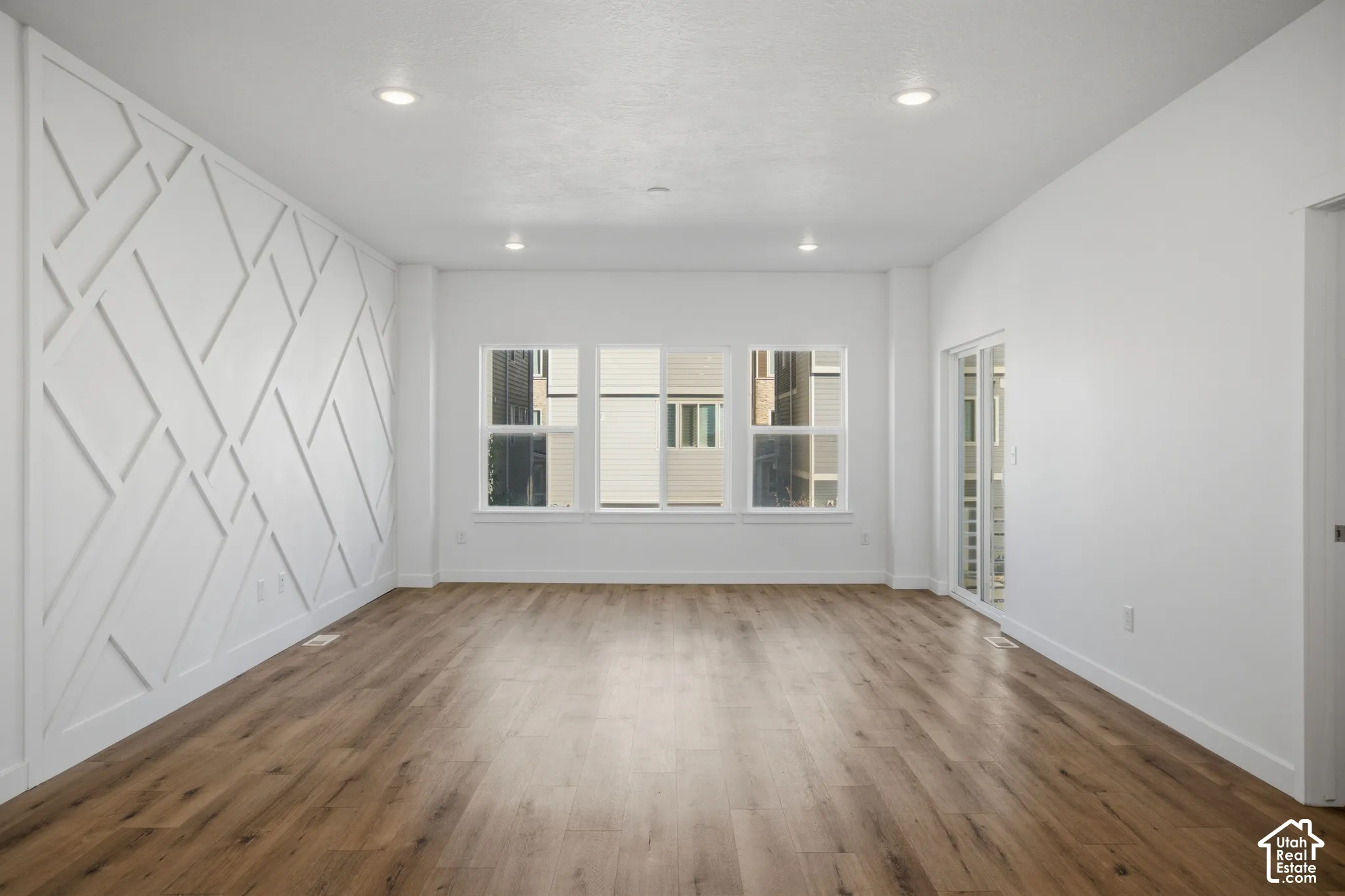 Interior space featuring wood-finish flooring, recessed lighting, and a geometric accent wall treatment