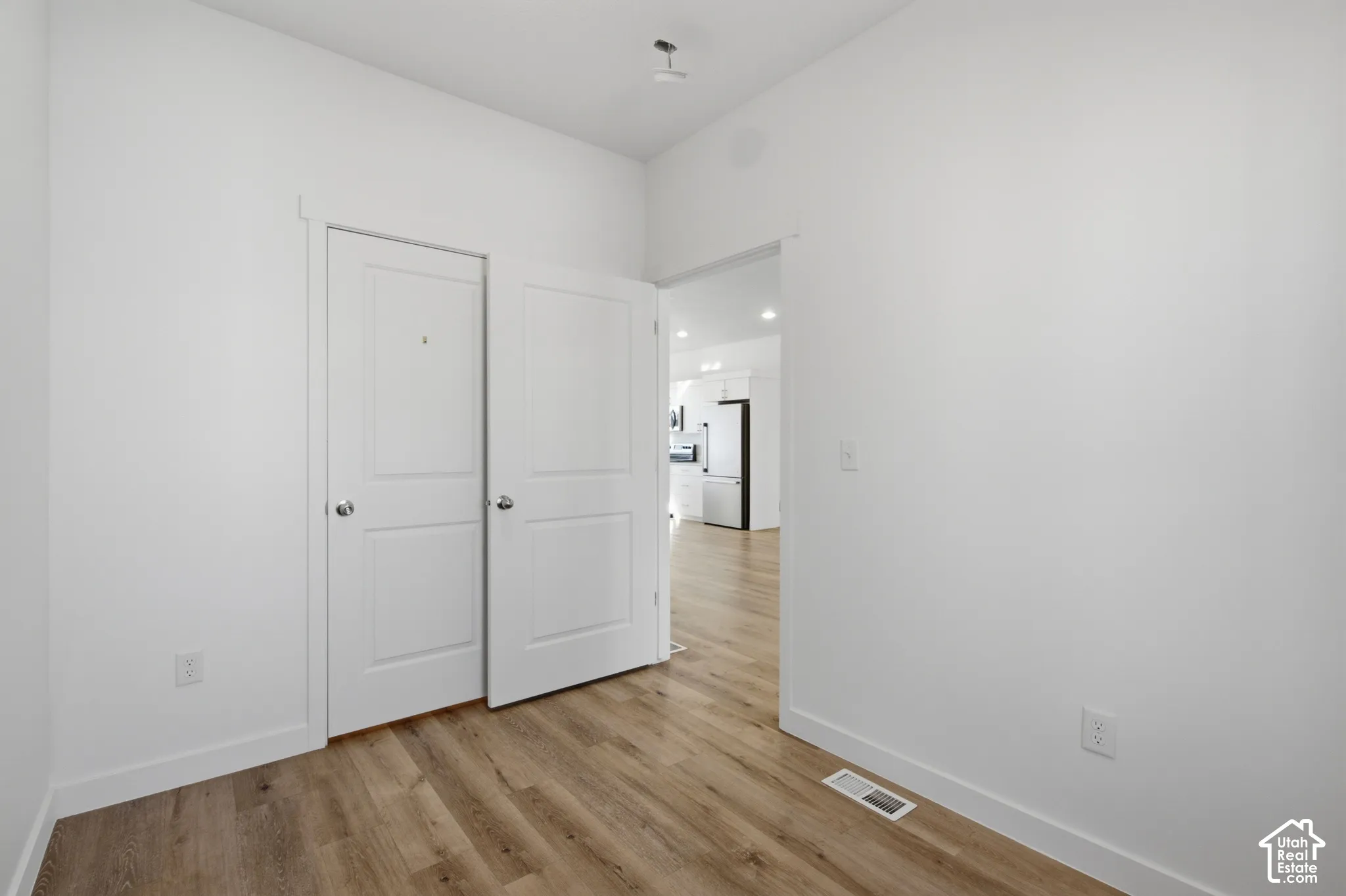 Room featuring wood-finish flooring, two-panel interior doors, and neutral wall tones