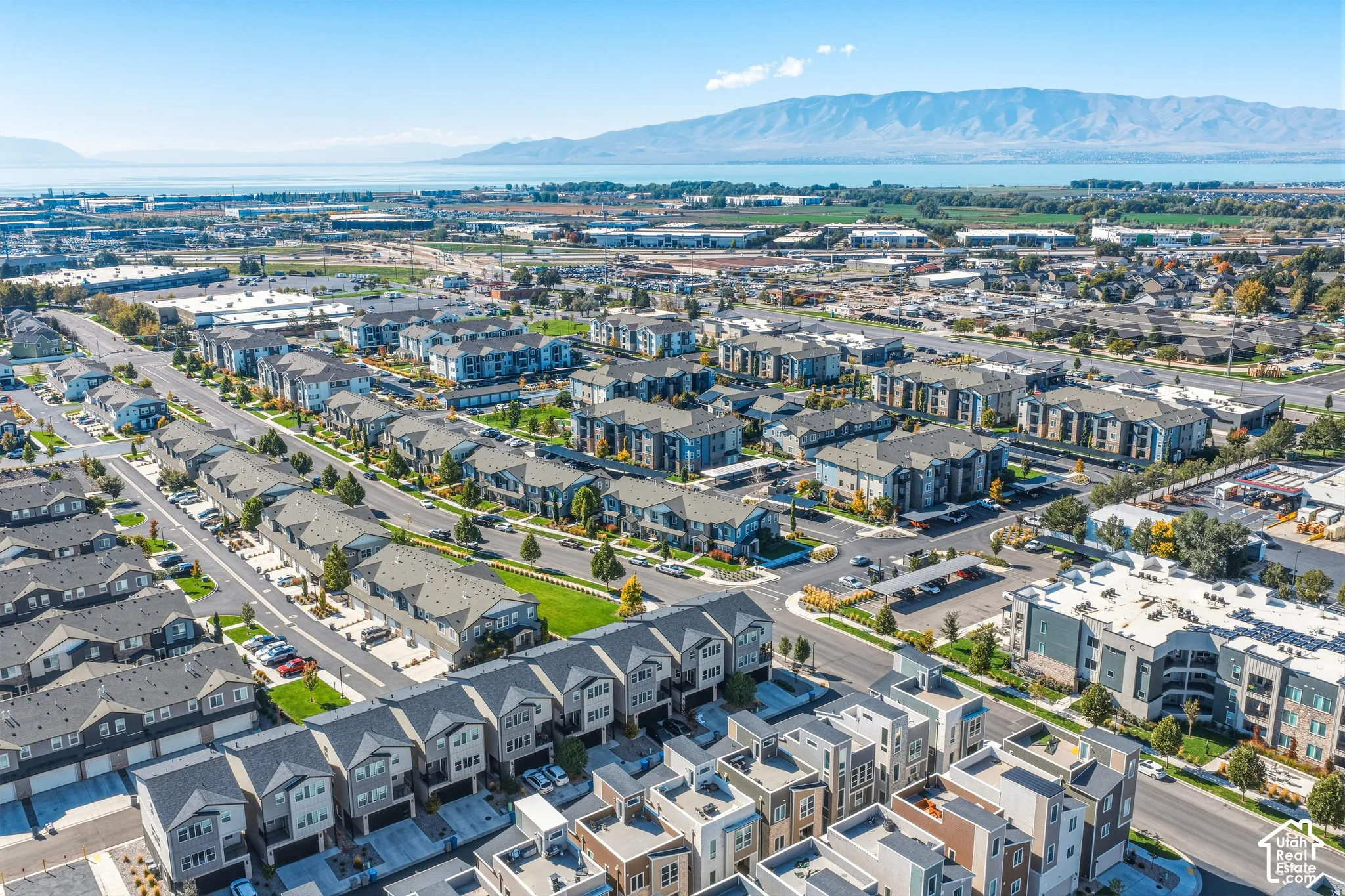 Aerial perspective of a multi-unit residential community featuring tiered rooflines, paved surface roadways, manicured green spaces, and a mountainous backdrop
