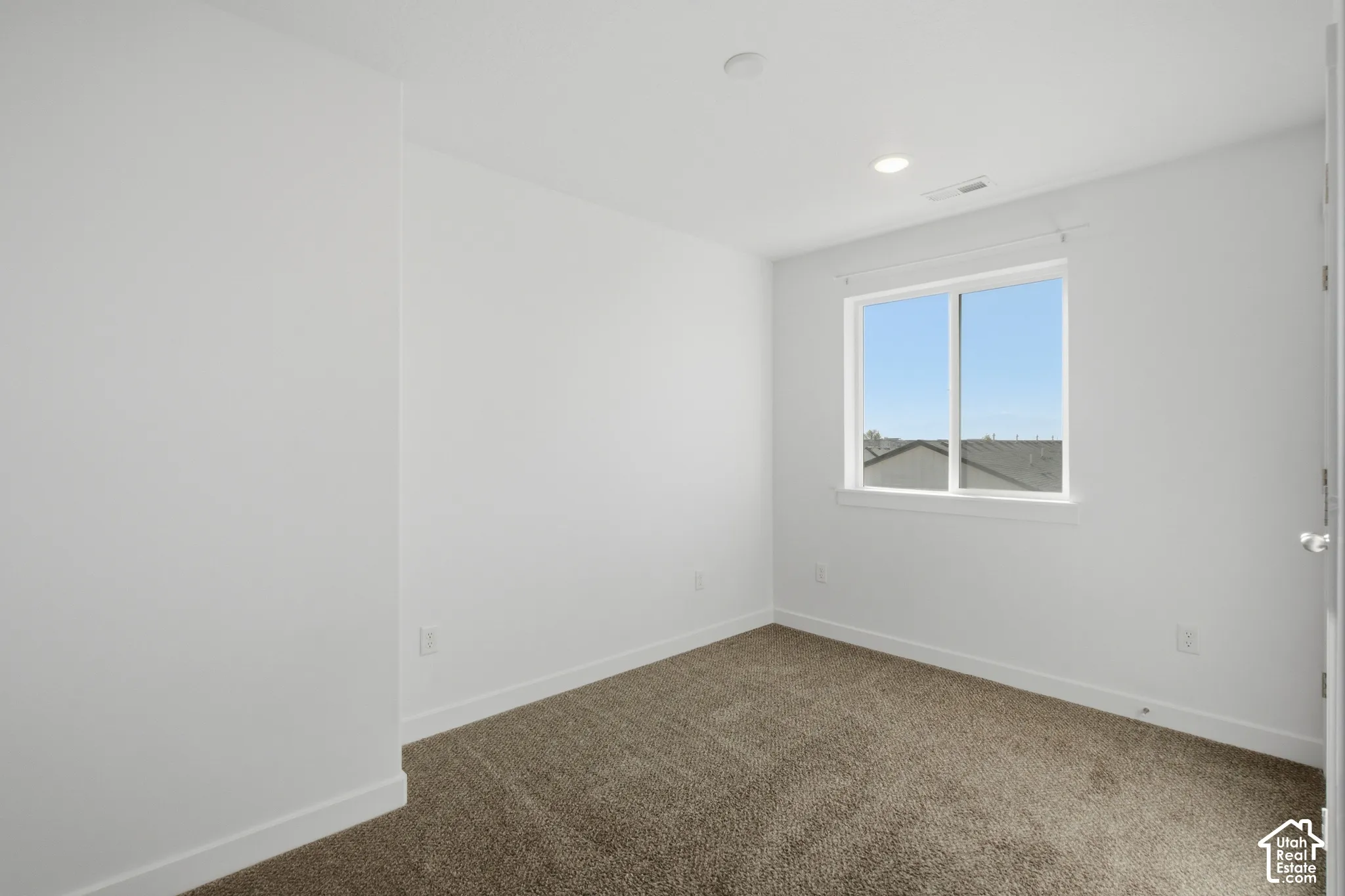 Neutral-toned wall-to-wall carpeting, crisp white walls, and a single-pane sliding window with white trim