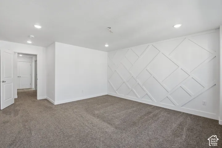 Interior space featuring wall-to-wall carpeting, recessed ceiling lighting, and a geometric wood wall treatment