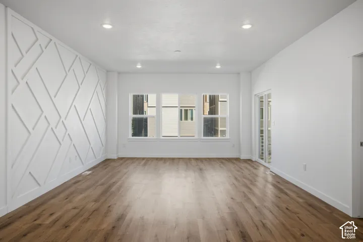 Interior space featuring wood-finish flooring, recessed lighting, and a geometric accent wall treatment