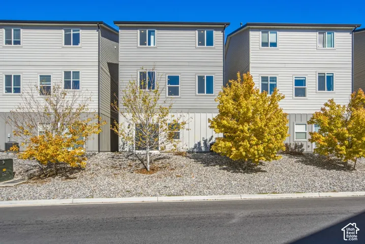 Three-story townhome exterior featuring horizontal lap siding, vertical board-and-batten detailing, and multi-pane windows