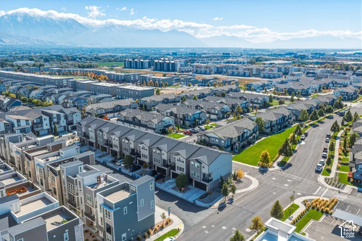 Aerial perspective of residential community featuring mountain backdrops, multi-level townhome exteriors, paved street infrastructure, and manicured green spaces